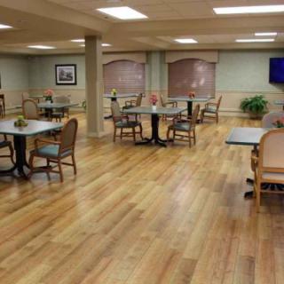 An empty dining area with wooden floors and neatly arranged tables and chairs.