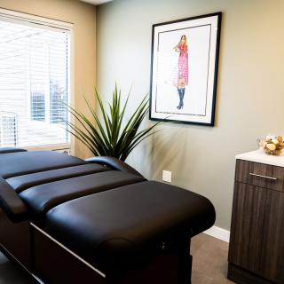 A serene therapy room with a massage table, modern decor, and natural light.