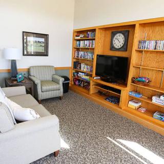 A cozy living room with comfortable seating and a wooden bookshelf featuring a TV, books, and decor items.