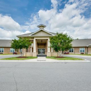 A large building with an impressive entrance surrounded by manicured landscaping and under a partly cloudy sky.