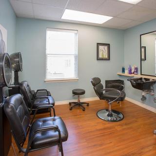 A cozy salon interior with chairs, mirror, and hair styling equipment.