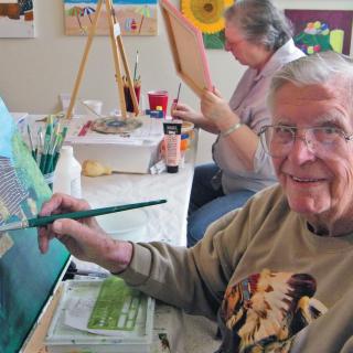 Elderly individuals enjoy painting in a relaxed art class setting.