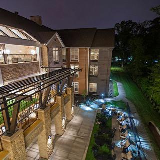 A well-lit building at night, with a pathway and surrounding greenery.