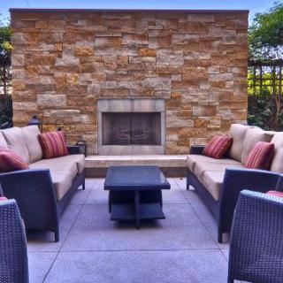 A cozy outdoor patio with comfortable seating and a stone fireplace.