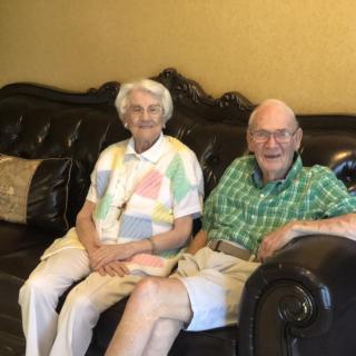 An elderly couple sitting together on a sofa in a living room.