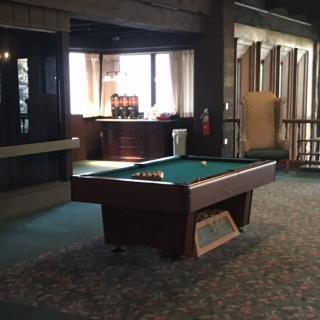 A dimly lit game room featuring a pool table with billiard balls set up.