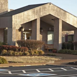 A modern concrete building entrance with landscaped surroundings.