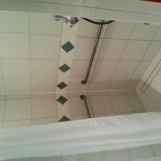 A view of a shower area with tiled walls and a shower curtain.