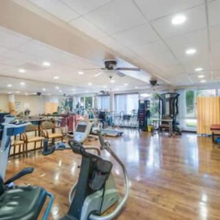 A spacious gym with various exercise equipment and a wooden floor.