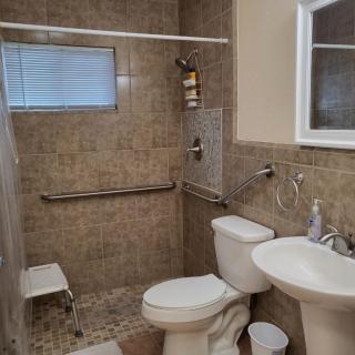 A tiled bathroom with a shower area, toilet, and pedestal sink.
