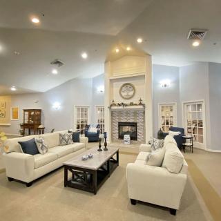 A modern living room with white couches, a central fireplace, and bright lighting.
