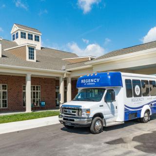 A shuttle bus parked in front of a building on a sunny day.
