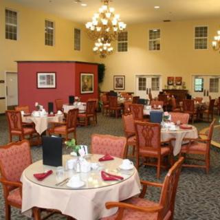 An elegant dining room with neatly arranged tables and chairs, featuring chandeliers and decorative elements.