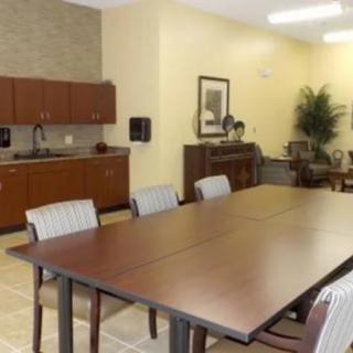A well-furnished conference room with a long meeting table, surrounded by chairs and equipped with cabinets.
