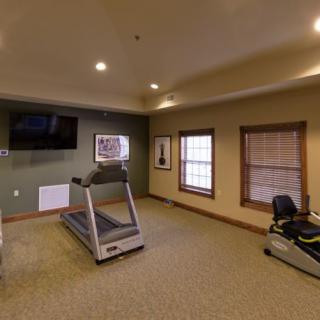 A small gym room with a treadmill and exercise machine.