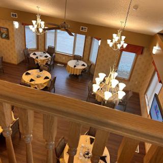 A cozy and elegant dining area with a view, complete with chandeliers and neatly set tables.