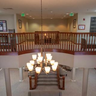 A spacious interior featuring a grand staircase with an elegant chandelier and upper balcony.