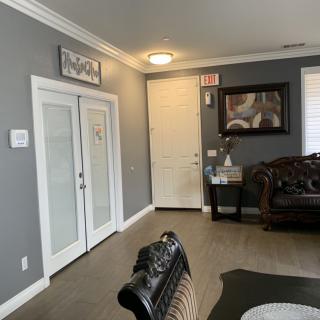 A cozy living room with elegant furniture and decor, featuring a sofa, a painting on the wall, and double doors.