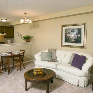 A cozy living room with a white sofa, coffee table, and an adjoining dining area.