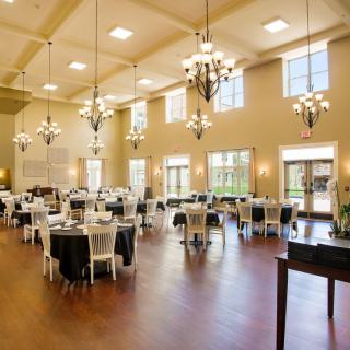 A spacious banquet hall with elegant chandeliers and neatly arranged tables, ready for an event.