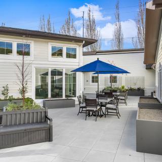 A modern patio with outdoor seating and an umbrella, set against a contemporary house exterior.