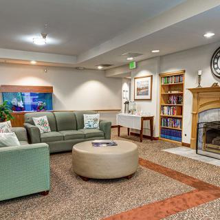 A cozy living room with a fireplace, sofas, a bookshelf, and decorative elements.