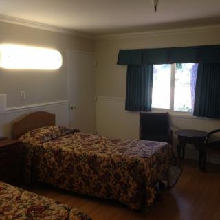 A simple hotel room with two beds and a window with curtains.