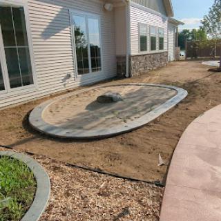 A newly prepared outdoor space with a partially completed patio area featuring a stone outline.