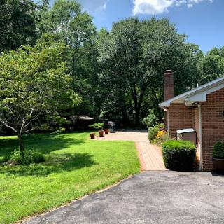 A serene outdoor scene featuring a well-maintained garden and a home, surrounded by lush greenery on a sunny day.