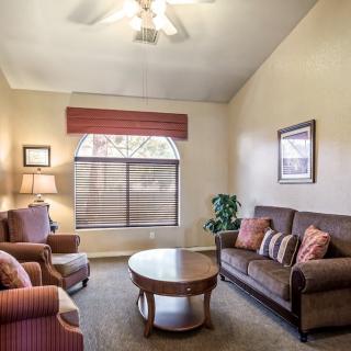 A cozy living room with a sofa, armchairs, and a coffee table near a large window.