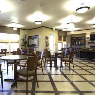 A spacious dining area with multiple tables and chairs, featuring modern lighting and a tiled floor.
