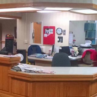 An empty reception area with a desk, chairs, and computer equipment.