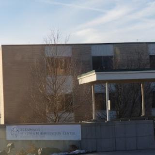 A modern building surrounded by trees on a clear day.