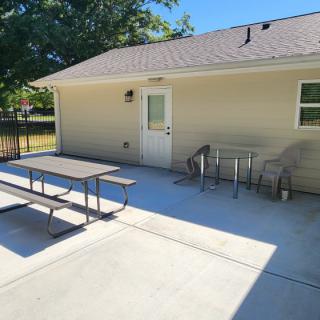 Sunny backyard patio with a picnic table and chairs.