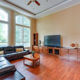 A spacious living room with a large sofa, flat-screen TV, and hardwood floors.