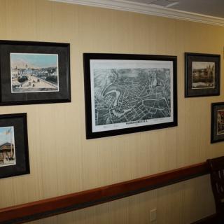 A collection of framed pictures and a map displayed on a wall in an interior setting.