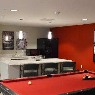 A stylish game room featuring a red pool table and modern kitchenette, perfect for entertainment.