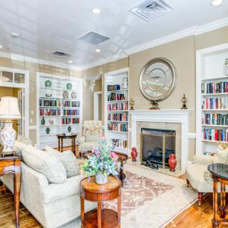 A cozy living room with elegant decor, featuring a fireplace surrounded by bookshelves and comfortable seating.