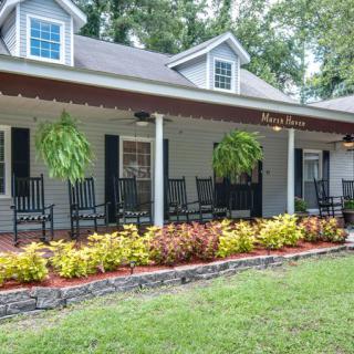 A charming house with a covered porch, featuring rocking chairs and well-maintained landscaping.