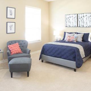 A modern and comfortable bedroom with a blue-themed bed, an armchair, and elegant decor.