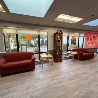 A cozy lounge area featuring comfortable seating with ample natural light streaming through large windows.