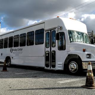 A white bus parked in a lot under a cloudy sky.