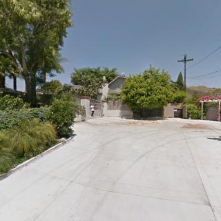 A suburban driveway leading up to a house surrounded by trees.