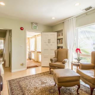 A bright and cozy living room with comfortable armchairs, a patterned rug, and large windows letting in natural light.