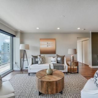 A modern living room with stylish furniture and a large window offering a city view.