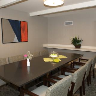 A modern dining room with a large table, surrounded by chairs and decorated with artwork and plants.