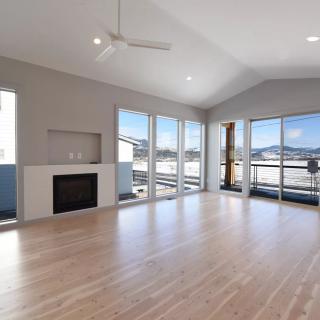 A modern living room with hardwood floors, large windows, and a fireplace.