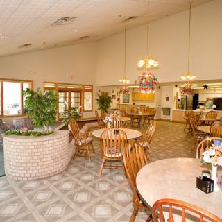 An inviting dining area with wooden tables and chairs, complemented by indoor plants and warm lighting.