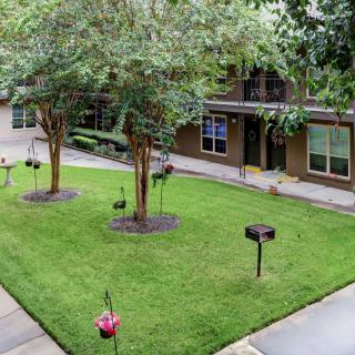 A serene apartment courtyard with well-maintained grass and trees.