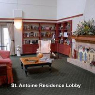 A cozy residential lobby with a bookshelf, armchair, and fireplace.